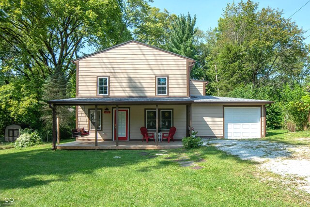 view of front of property featuring covered porch, a front yard, and a garage