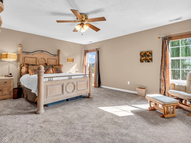 bedroom with light colored carpet, ceiling fan, and a textured ceiling