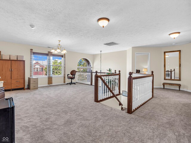 interior space with an inviting chandelier, a textured ceiling, and carpet floors