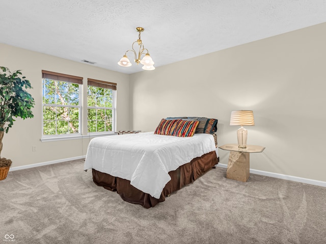 carpeted bedroom with a notable chandelier and a textured ceiling