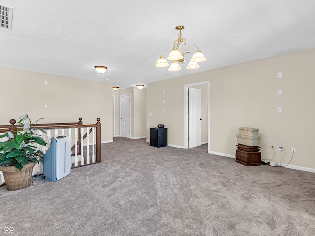 carpeted empty room featuring a textured ceiling and a chandelier