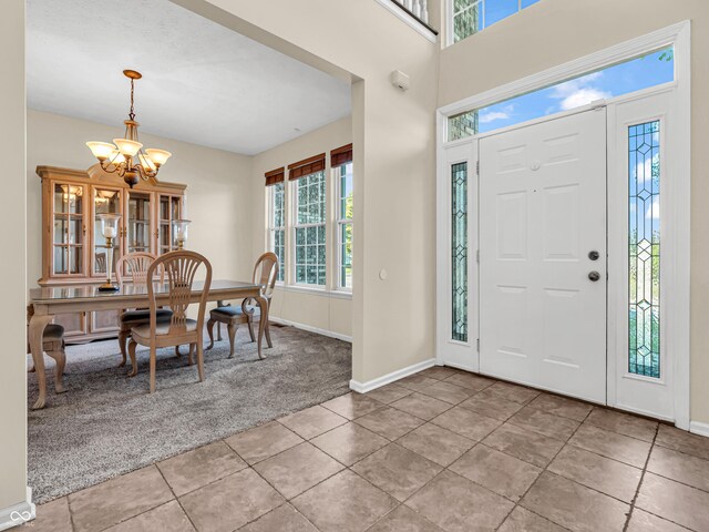 carpeted foyer entrance with an inviting chandelier