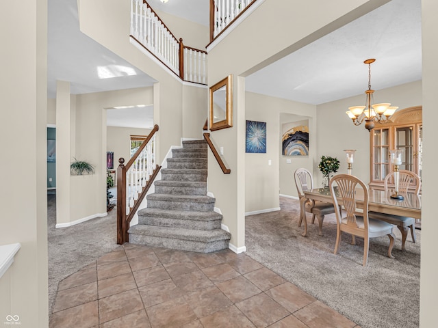 carpeted foyer entrance featuring a high ceiling and an inviting chandelier