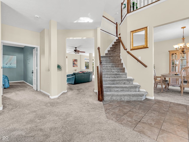 staircase featuring carpet flooring and ceiling fan with notable chandelier