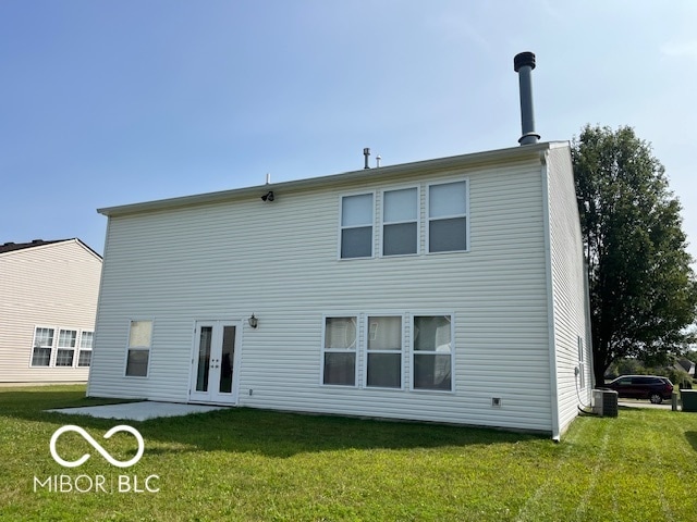 rear view of house with central AC unit, a yard, and french doors