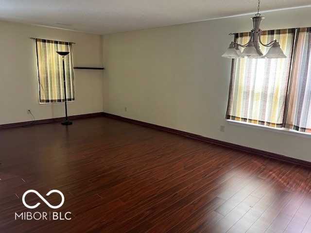 spare room featuring hardwood / wood-style floors and a chandelier