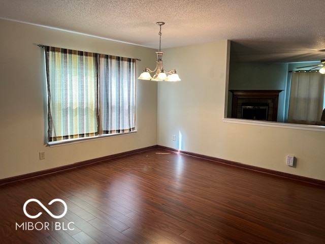 unfurnished room with a textured ceiling, ceiling fan with notable chandelier, and hardwood / wood-style floors