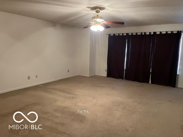 carpeted spare room featuring a textured ceiling and ceiling fan