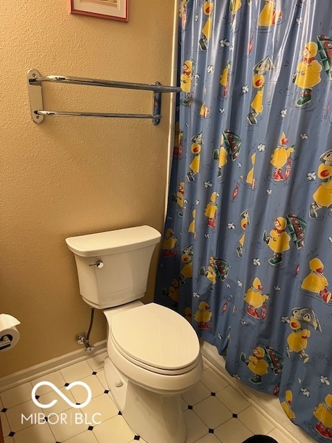 bathroom with toilet, tile patterned floors, and curtained shower