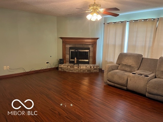 unfurnished living room featuring ceiling fan, a fireplace, a textured ceiling, and dark hardwood / wood-style floors