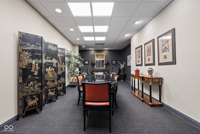 carpeted dining area with a paneled ceiling