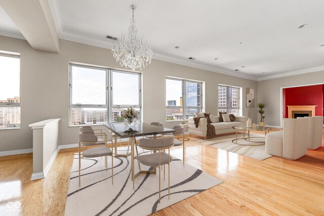 dining area with light wood-type flooring, an inviting chandelier, and ornamental molding