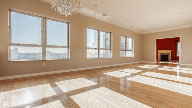 unfurnished room featuring ornamental molding, a notable chandelier, and light hardwood / wood-style floors