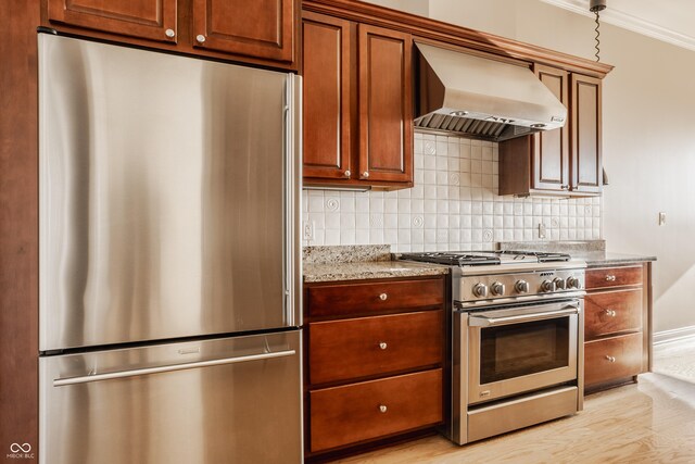 kitchen with backsplash, wall chimney range hood, light stone countertops, appliances with stainless steel finishes, and light hardwood / wood-style floors