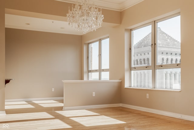 unfurnished room featuring light wood-type flooring, a chandelier, and crown molding