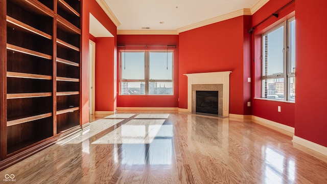 unfurnished living room featuring a healthy amount of sunlight, crown molding, and light hardwood / wood-style flooring