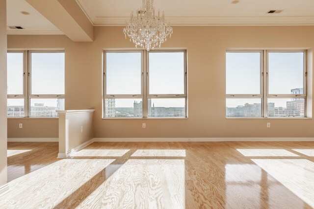 unfurnished room with crown molding, an inviting chandelier, and light wood-type flooring