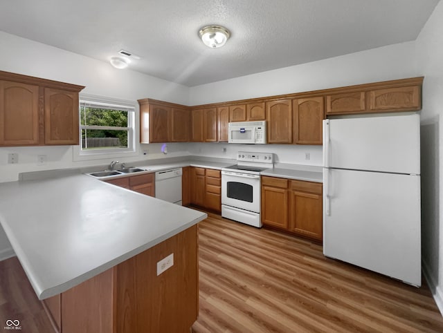 kitchen featuring sink, kitchen peninsula, hardwood / wood-style floors, and white appliances