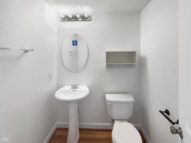 bathroom with a textured ceiling, hardwood / wood-style floors, and toilet