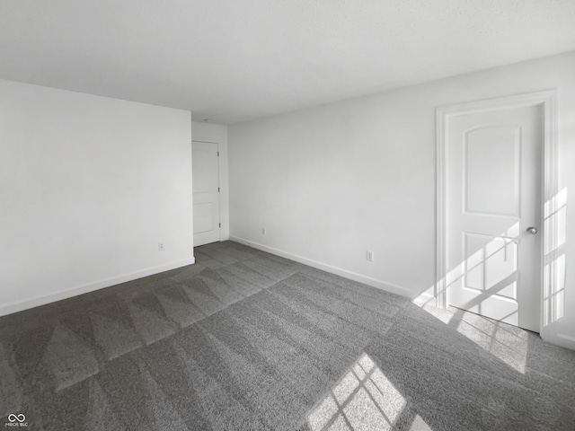 spare room with dark carpet