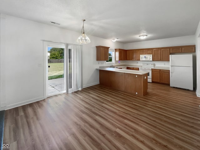 kitchen with decorative light fixtures, an inviting chandelier, dark hardwood / wood-style flooring, kitchen peninsula, and white appliances