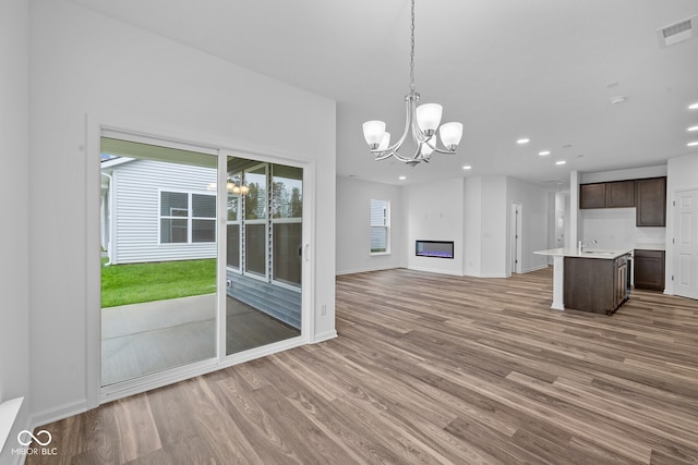 unfurnished living room with a notable chandelier, hardwood / wood-style flooring, and sink