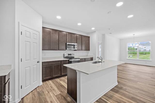 kitchen featuring light stone counters, wood-type flooring, stainless steel appliances, hanging light fixtures, and an inviting chandelier