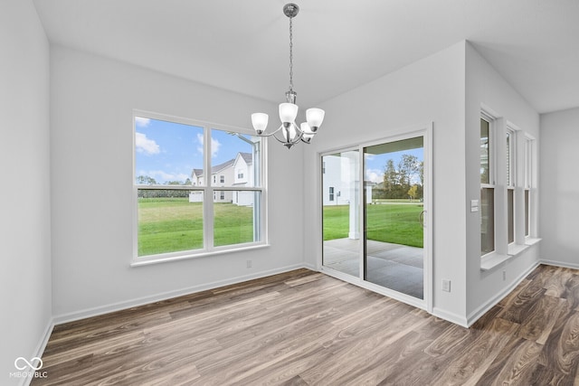 unfurnished dining area with a chandelier and wood-type flooring