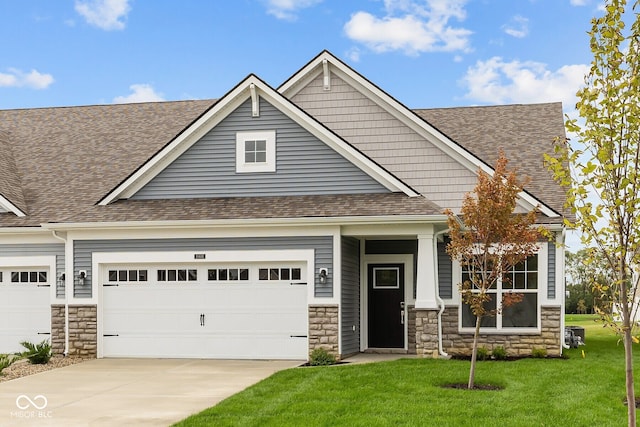 craftsman inspired home featuring concrete driveway, a shingled roof, and a front yard