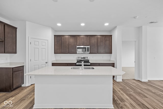 kitchen featuring an island with sink, hardwood / wood-style floors, and appliances with stainless steel finishes