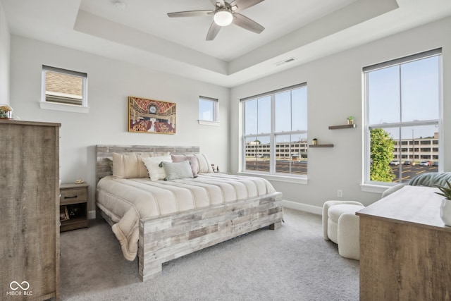 bedroom with ceiling fan, carpet flooring, and a raised ceiling