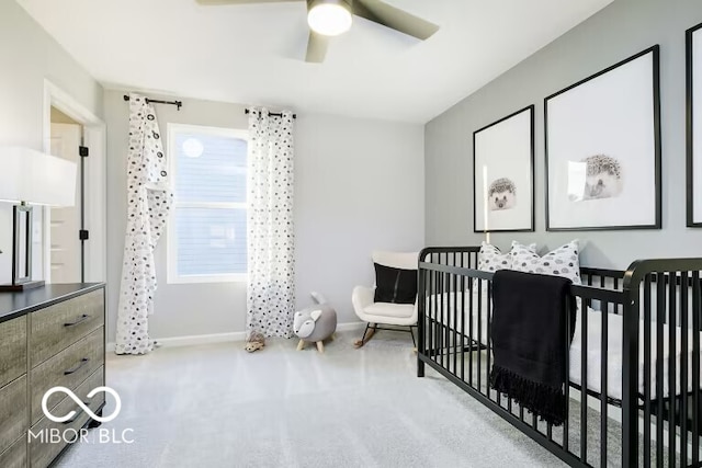 bedroom with light colored carpet, ceiling fan, and a crib