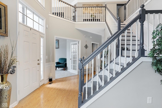 entryway featuring stairs, french doors, a towering ceiling, and wood finished floors