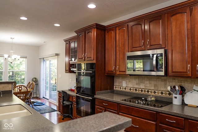 kitchen with an inviting chandelier, decorative light fixtures, black appliances, wood-type flooring, and sink