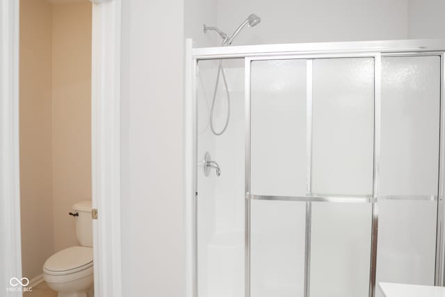 bathroom featuring toilet and an enclosed shower