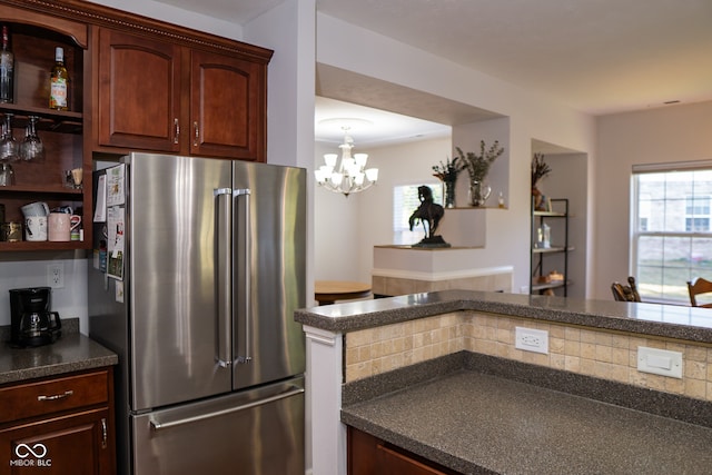 kitchen with plenty of natural light, an inviting chandelier, stainless steel fridge, and backsplash