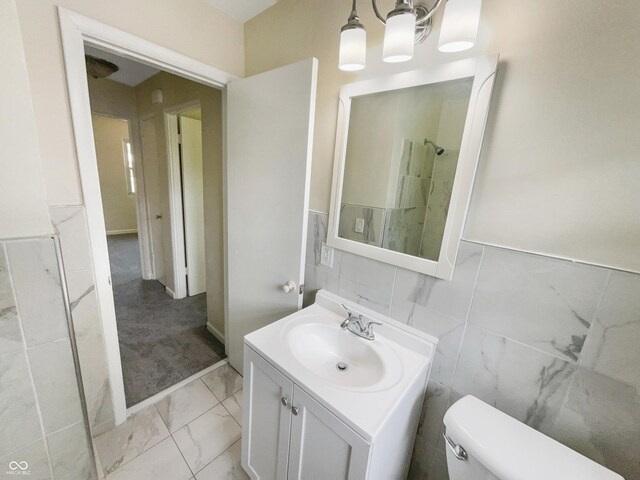 4013 N Graham Ave, Indianapolis, IN 46226 - bathroom with marble look tile flooring, vanity, toilet, tile walls, and wainscoting