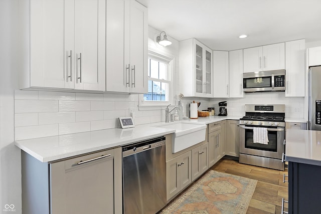 kitchen with sink, tasteful backsplash, light wood-type flooring, and stainless steel appliances