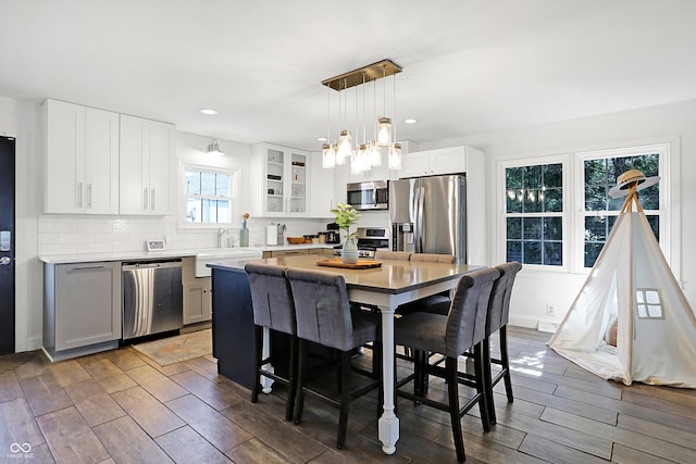 kitchen with dark hardwood / wood-style flooring, tasteful backsplash, white cabinetry, a center island, and stainless steel appliances