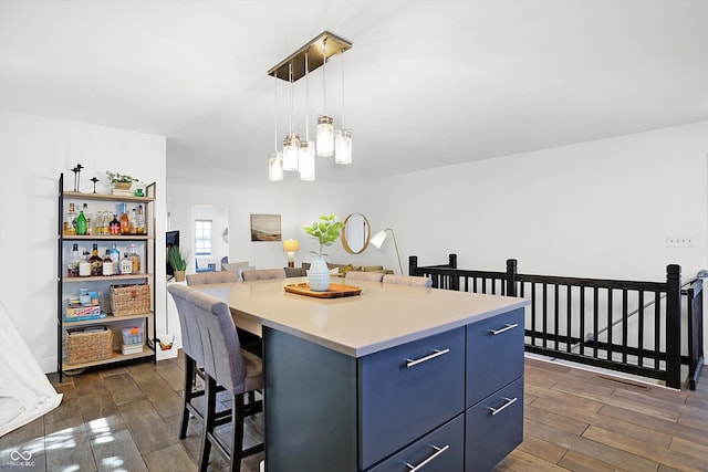 kitchen featuring decorative light fixtures, dark hardwood / wood-style floors, a kitchen island, a breakfast bar, and blue cabinets