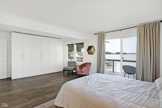 bedroom featuring access to outside, dark hardwood / wood-style flooring, and a water view