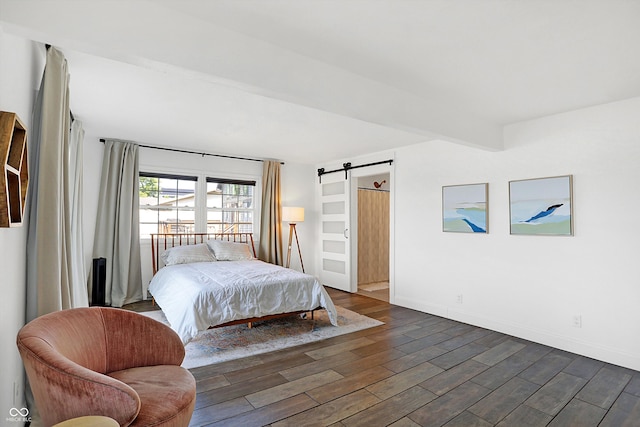 bedroom with beam ceiling, dark hardwood / wood-style floors, and a barn door