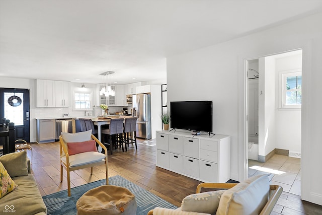 living room with light hardwood / wood-style floors, a notable chandelier, and plenty of natural light