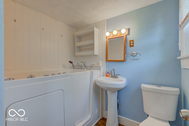 bathroom with a textured ceiling, toilet, and sink