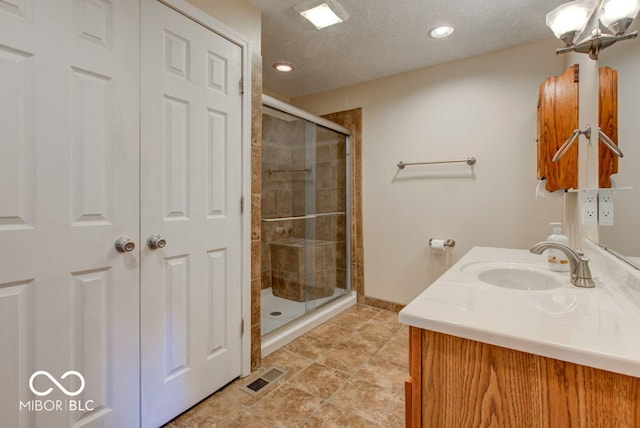 bathroom featuring a textured ceiling, a shower with door, and vanity