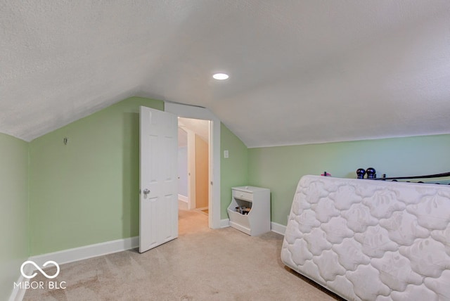 carpeted bedroom with vaulted ceiling and a textured ceiling