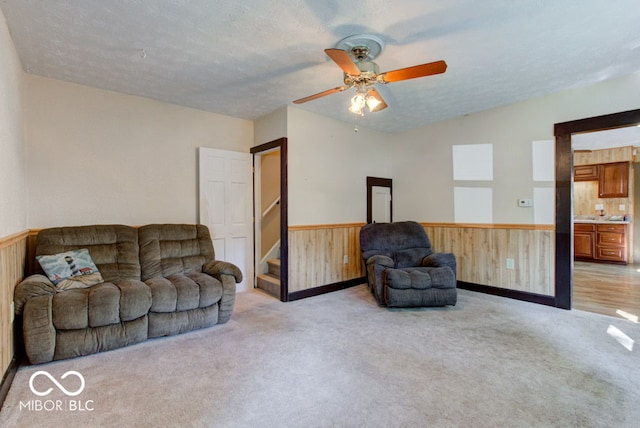 living room featuring wooden walls, light carpet, and ceiling fan