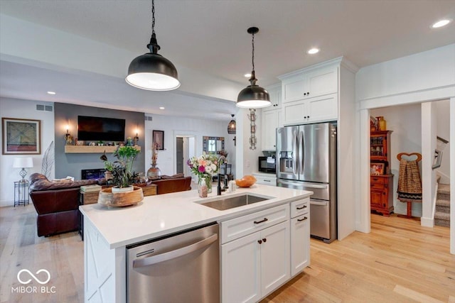 kitchen with visible vents, appliances with stainless steel finishes, open floor plan, white cabinets, and a sink