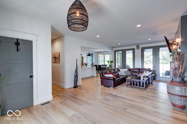 living room with light wood finished floors, french doors, visible vents, and a healthy amount of sunlight