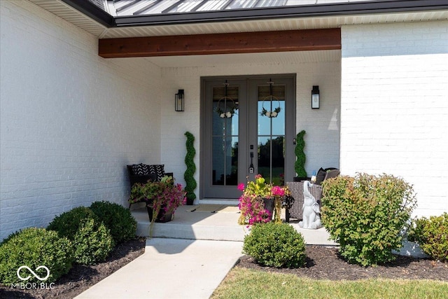 doorway to property featuring french doors, brick siding, metal roof, and a standing seam roof